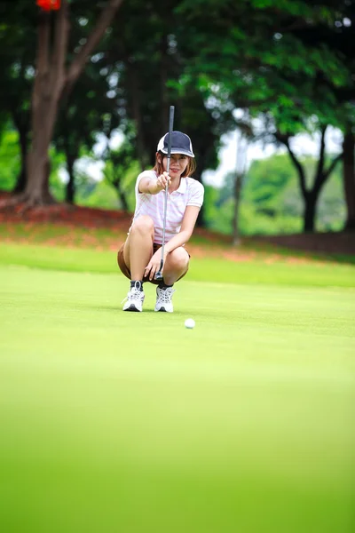 Jugadora de golf femenina con putter en cuclillas para analizar el verde —  Fotos de Stock