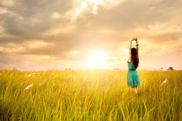 Happy young asian woman standing in meadows with sunset — Stock Photo, Image