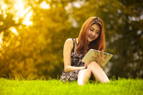 Mulher asiática usando tablet digital no parque — Fotografia de Stock