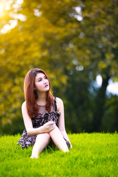 Bela jovem ásia mulher sentado no verde grama — Fotografia de Stock