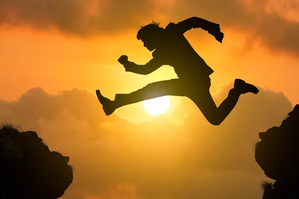 Silhouette businessman jump through the gap — Stock Photo, Image