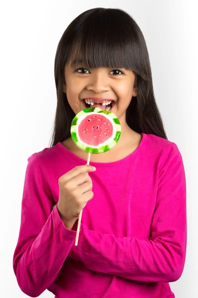 Feliz poco asiático chica y roto dientes holding un lollipop —  Fotos de Stock