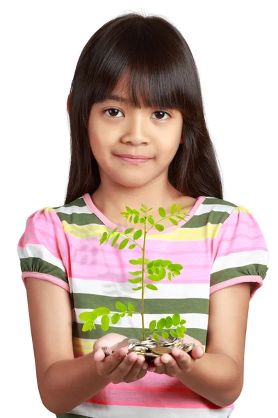 Маленькая азиатская девочка с ростом саженцев из монет — стоковое фото