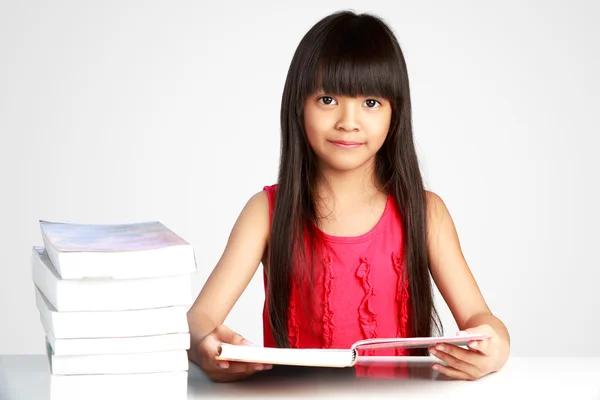 Pequeña chica asiática con libros en la mesa — Foto de Stock