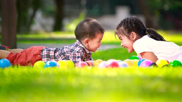Dvě děti, se kterým se na zelené trávě a úsměv — Stock fotografie