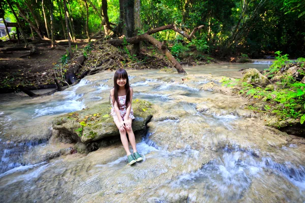 Petite fille assise sur la pierre dans un ruisseau forestier — Photo