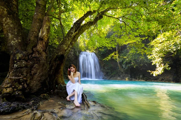 Young woman relaxing in water stream near waterfall