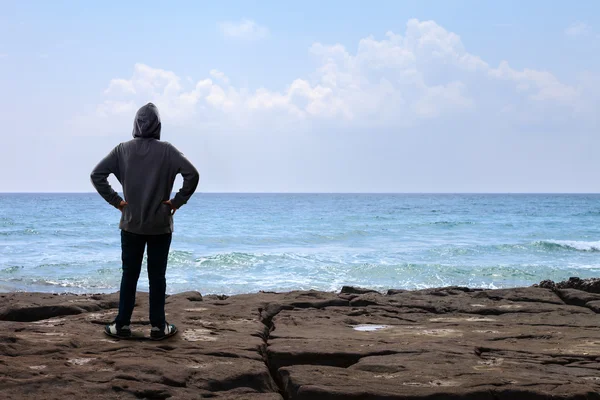 Tonåring pojke står på berget och ser till havet — Stockfoto