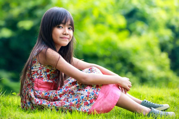 Jovem menina asiática sentado no verde — Fotografia de Stock