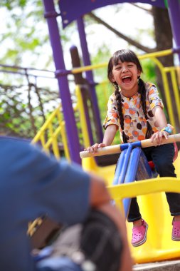 Asyalı küçük kız, bir çocuk oyun alanı içinde oynamaktan hoşlanıyor.
