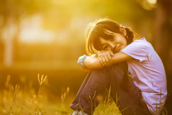 Счастливая девушка сидит на траве в саду — стоковое фото