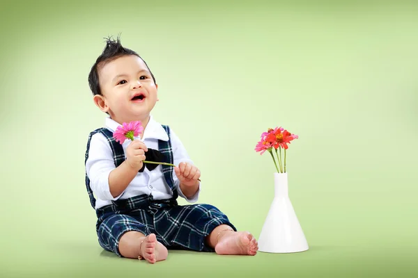 Menino bonito com bela flor sentada no chão — Fotografia de Stock