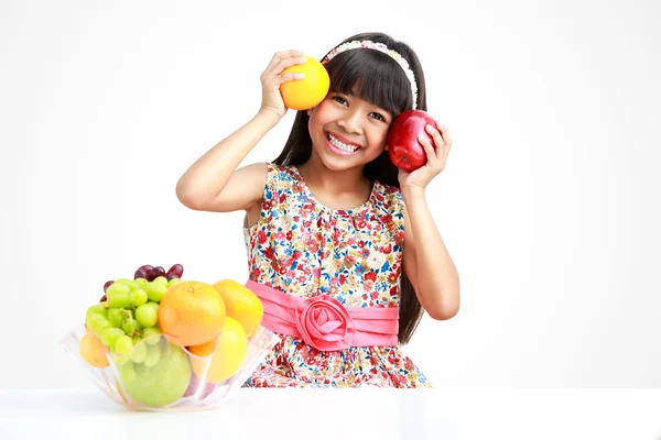 과일 접시와 함께 테이블에 앉아 행복 한 작은 아시아 소녀 — 스톡 사진