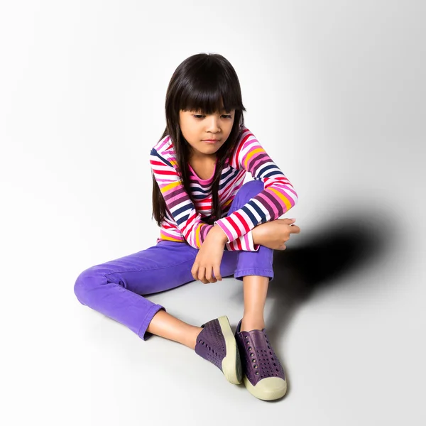 Ledsen liten flicka sitter på golvet — Stockfoto