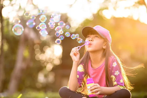 Little asian girl blowing soap bubbles — Stock Photo, Image