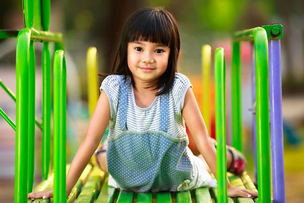 Petite fille asiatique assis sur la glissière à l'aire de jeux — Photo