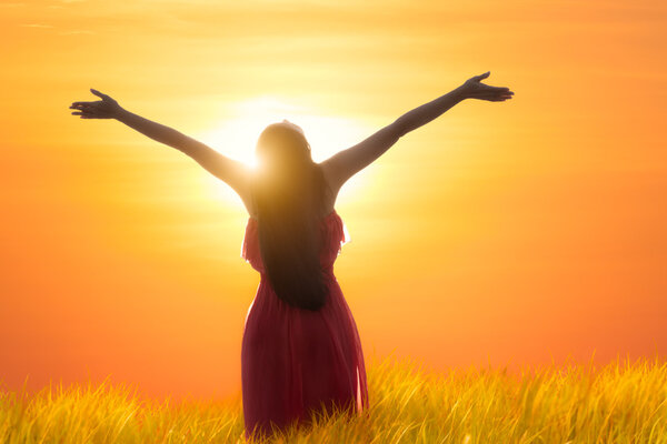 Young asian woman standing open her arms under the sunrise