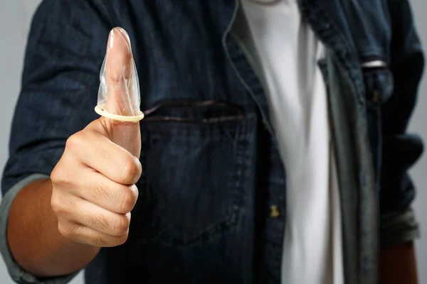 Man holding the condom on the thumb — Stock Photo, Image