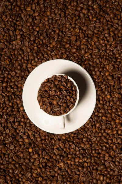 濃い背景にコーヒー豆を入れたカップ — ストック写真