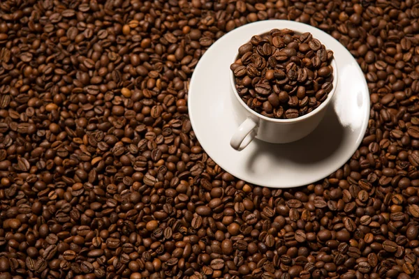 Xícara com grãos de café em um fundo escuro — Fotografia de Stock