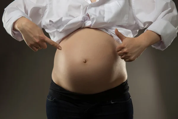 Zwangere vrouw doen ok teken en wijst haar bell — Stockfoto