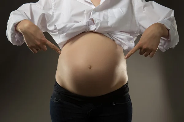 Mulheres aponta para o fundo de sua barriga — Fotografia de Stock