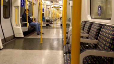 Londra, İngiltere, UNITED KINGDOM - CIRCA NOVEMBER, 2020: Neredeyse boş Londra metro vagonları veya metro vagonları, sadece çok az kişi kıpırdayan bir yeraltı treninde oturuyor.