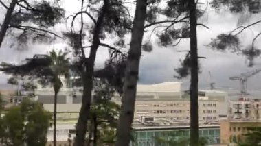 Demiryolu treninin penceresinden Castellammare di Stabia 'nın binaları ve vinçleri görünüyor. Napoli' nin metropolitan şehri ağaçların arasından geçiyor..