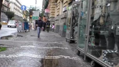 NAPLES, ITALY - OCTOBER, 2016: Handheld camera personal point of view, POV walking on sidewalk by store and crossing Corso Umberto I street in Naples.