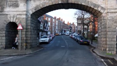 CHESTER, İngiltere, BİRLİK KINGDOM - JANUARY, 2022: Arabalar sürüyor ve insanlar Bridgegate kemerinden geçiyorlar, 12. yüzyılda Romalılar tarafından inşa edilen şehir duvarının bir parçası..