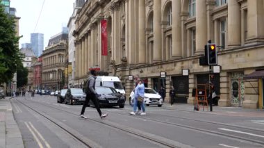 MANCHESTER, İngiltere, BİRLİK KINGDOM - CIRCA EPTEMBER, 2021: Şehir merkezindeki Royal Exchange Tiyatrosu 'nun önünde karşıdan karşıya geçen insanlar.