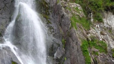 Yakından bakınca, İngiltere 'nin Galler' deki Snowdonia Ulusal Parkı 'nda yeşil yemyeşil sulak ve kayalarla çevrili çarpıcı Aber Şelalesi görüntüsü görülüyor..