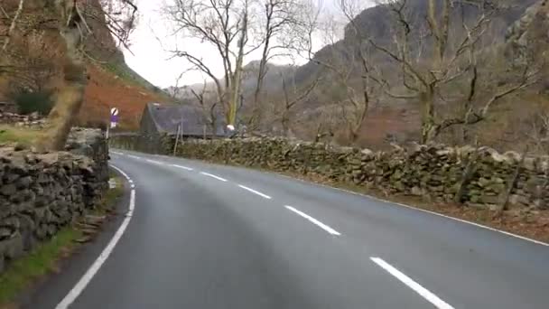 運転は秋に小さなウェールズの村を介してスノードニア山脈のLlanberisからA4086道路を巻き石の壁フェンスで囲まれた — ストック動画