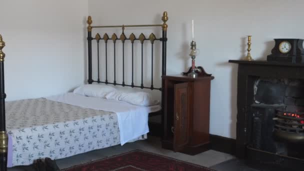 英国のレトロスタイルの寝室で暖炉の上に古い金属製のベッドと時計を示すパンニングショット — ストック動画