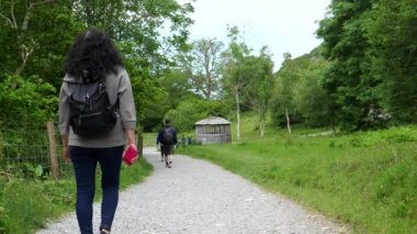 Kuzey Galler 'deki Snowdonia Ulusal Parkı' ndaki çakıllı patikada birbiri ardına yürüyen üç kişilik grup ya da ailenin arka görüntüsü..