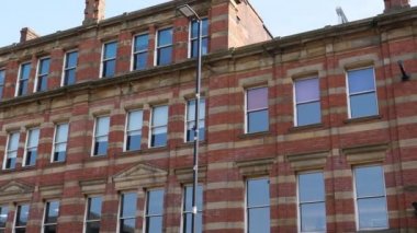 İngiltere 'deki şehir merkezi caddesindeki dükkanların üstündeki kırmızı tuğlalı teraslı binanın görüntüsü; gökyüzü boşluğu kopyala.