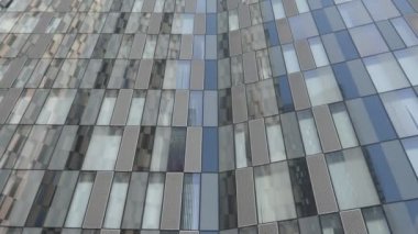 Damalı ya da ekoseli gökdelen dış cam duvar arkaplanı mavi gökyüzüne doğru eğiliyor ve iki binanın daha tepesini gösteriyor.