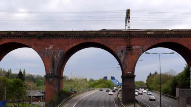 İngiltere 'nin Stockport kentindeki M60 otoyolunun üzerinde ünlü kemerli viyadük yolundan geçen iki elektrikli yolcu treni..