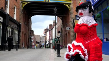 Kimliği belirlenemeyen üst düzey bir adam cep telefonuyla konuşuyor. Stockport 'un merkezinde, Greater Manchester' da kırmızı bez bebeğin yanından geçiyor..