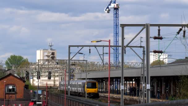 イギリス グレーターマンチェスターのストックポートに鉄道駅の建物を離れる短い電気旅客列車の後部ビュー — ストック動画