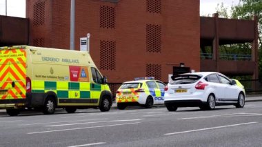 STOCKPORT, GREATER MANCHESTER, ENGLAND, UNITED KINGDOM - 04.18.2022: Traffic passing two police cars and ambulance van on opposite side of Wellington Road North.