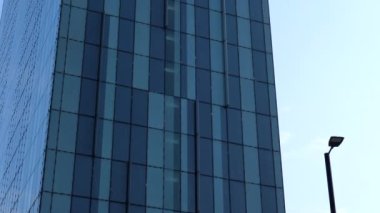 Handheld low angle tilt up shot of one blue color skyscraper building, plenty of sky copy space.