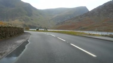 Kuzey Galler 'de sonbaharda Llyn Ogwen Gölü' nde A5 yolundan giden araba ön cam manzarası.