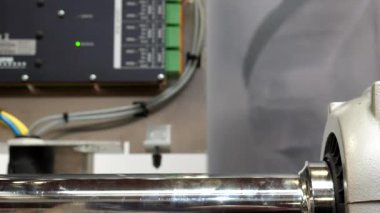 Parlak tüp döndürme, arka planda makine kontrol panelinde yanıp sönen yeşil gösterge ışığı, ön planda seçici odak.