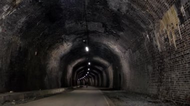 İngiltere 'nin Peak District Ulusal Parkı' ndaki ünlü Monsal Patikası 'nın bir parçası olan Cressbrook Tüneli' nin içinde bisiklet süren tanımlanamayan kavisli kadının uzaktan görüşü..