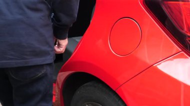 Sevgili görüntüsü yakın. Kotlu bir adam. Kırmızı renkli arabanın sol arka koltuğundan iniyor..