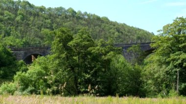 İngiltere 'de Peak District Ulusal Parkı' nda kullanılmayan demiryolu viyadük veya köprü üzerinde çok az kişi var; Monsal Dale, Wye Vadisi 'nden manzara.