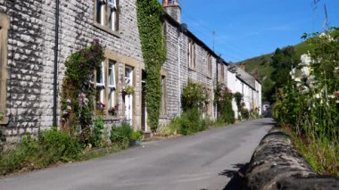 Küçük yerleşim birimlerinde dağcılık bitkileri ve çiçeklerle süslenmiş sıra sıra beyaz evler, Millers Dale, Peak District Ulusal Parkı, Birleşik Krallık.