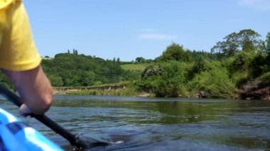 Woman paddling a double kayak on wide river Wye in South Wales, rear view of her right hand with an oar.