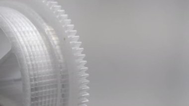 Close up of grey plastic cogwheel or gear rotating back and forth, copy space.